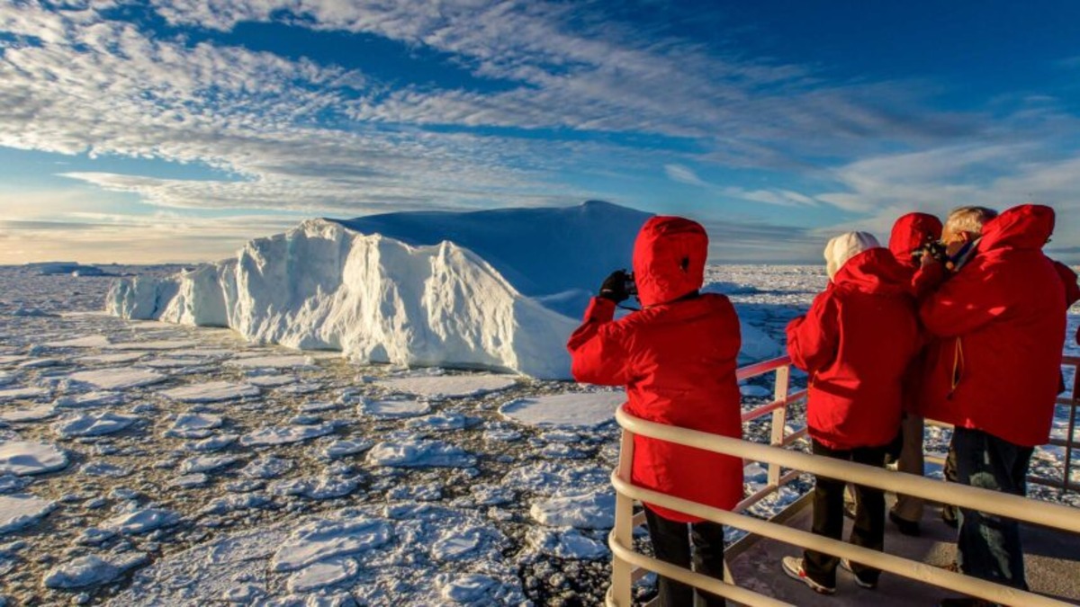 "Tourists and researchers in Antarctica with melting snow and ice, highlighting environmental impact of human activity"