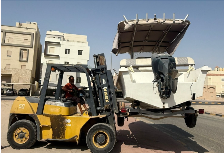 Kuwait Municipality workers removing abandoned vehicles and replacing old waste containers during a cleanup operation in Mubarak Al-Kabeer Governorate.